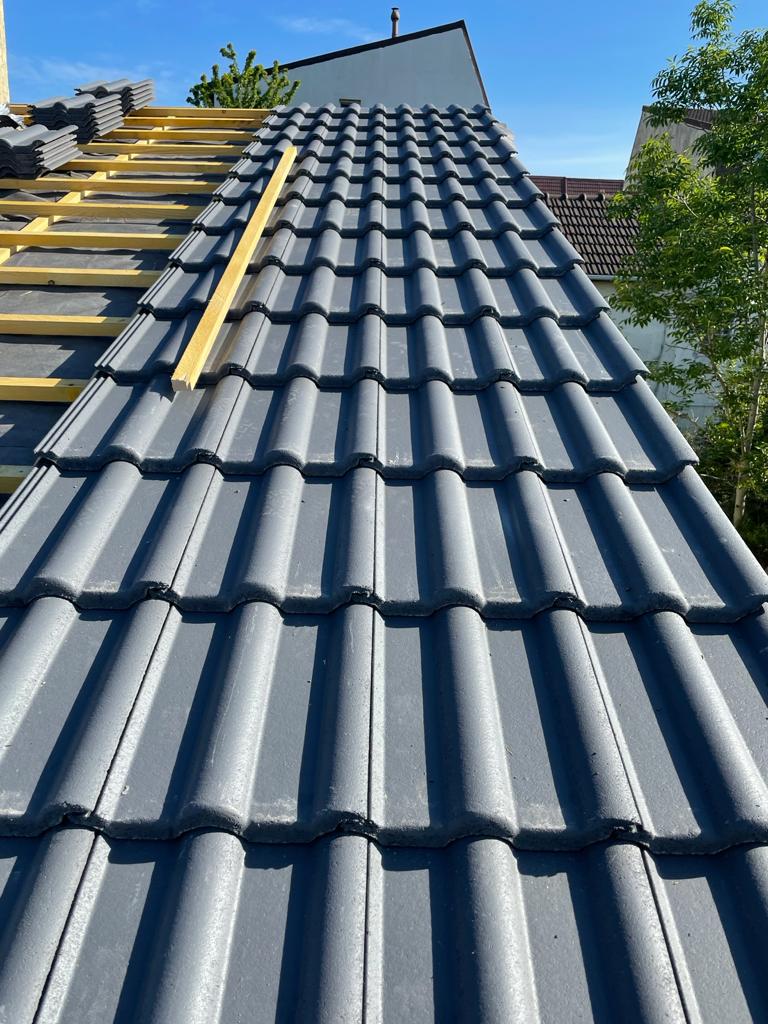 Couverture en tuiles anthracite à la teinte uniforme, rive et faîtage terminés