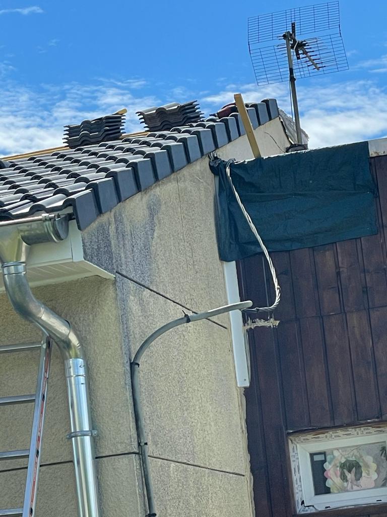 Descente d’eaux pluviales et gouttière posées le long du pignon d’une maison